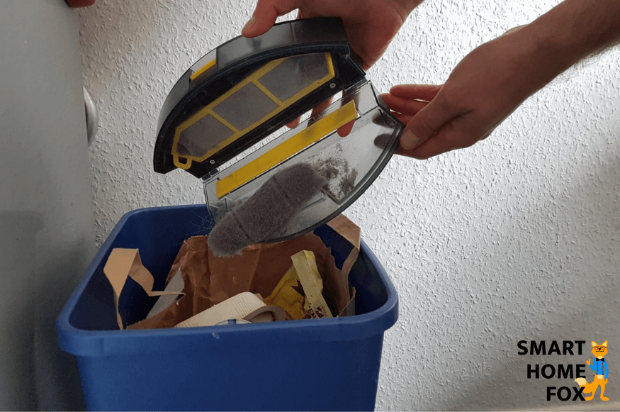 Mobiler Staubbehälter eines Saugroboters wird per Hand über einem Mülleimer ausgeleert